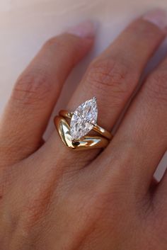 a woman's hand with a gold ring and a pear shaped diamond on it