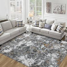 a living room filled with furniture and a rug on top of a hard wood floor