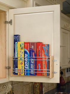 the kitchen cabinet door is open and has several cans on it, as well as a pull out spice rack