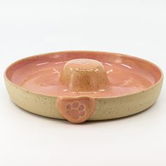 a dog bowl with a paw print on the bottom and a pink base in the middle