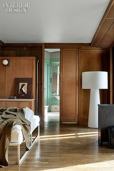 a bedroom with wood paneling and white bed in the corner, next to a large window