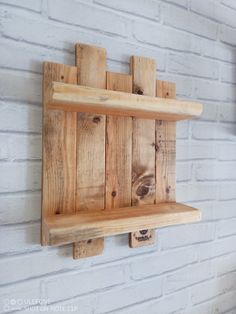 a wooden shelf mounted to the side of a white brick wall