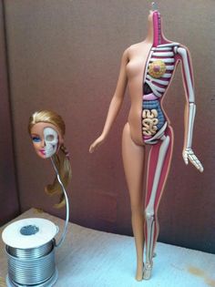 a doll is posed next to a tin can with a skeleton on it and an ipod in the foreground