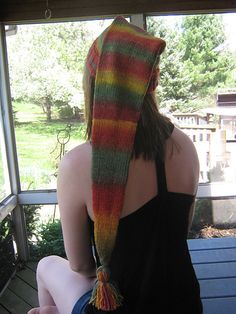 a woman sitting on a porch wearing a multicolored scarf