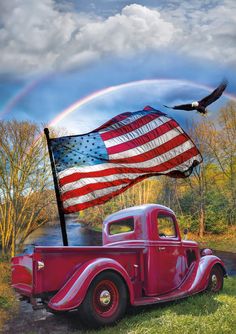 an old red truck with the american flag on it's side and a rainbow in the background