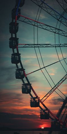 a ferris wheel with the sun setting in the background