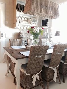 a dining room table with wicker chairs and baskets on the top shelf above it