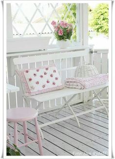 a white bench sitting on top of a wooden floor next to a pink table and chair