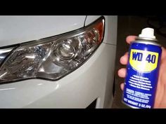 a person is holding a spray of cleaner next to a car's headlight