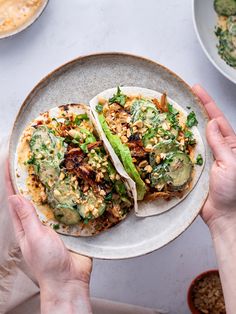 two tacos on a plate being held by hands