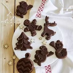 some cookies are on a white plate with red and white stars around them, along with one cookie in the shape of a christmas tree