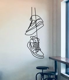 a wall with a drawing of shoes hanging from it's side in front of a window