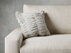 a white couch with two pillows on it's back and one pillow that has been turned down