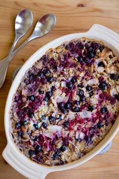 blueberry baked oatmeal in a white dish with two spoons next to it