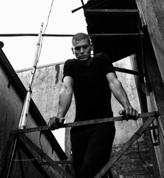 a man is walking up some stairs with his hands on the bars and looking at the camera