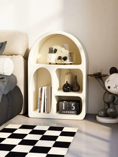 a white shelf with books and other items on it next to a black and white checkered rug