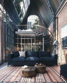 a living room filled with lots of furniture next to a spiral staircase leading up to a loft