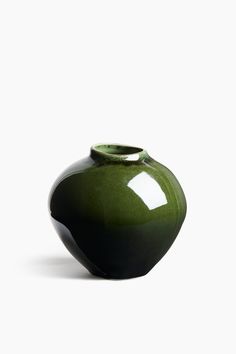 a green vase sitting on top of a white table