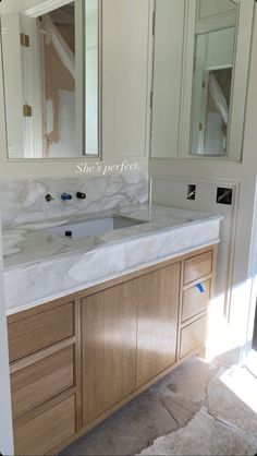 a bathroom vanity with marble counter top and wooden cabinetry in front of the mirror