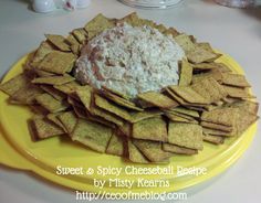 a yellow plate topped with crackers and a bowl of dip surrounded by cheese chips