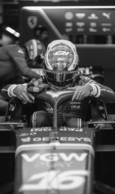 a man sitting in a race car with his hands on the steering wheel and wearing a helmet