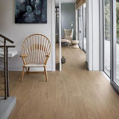 a chair sitting on top of a hard wood floor next to a window filled with lots of windows