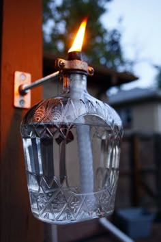 a glass bottle with a lighter attached to it's side hanging from a hook