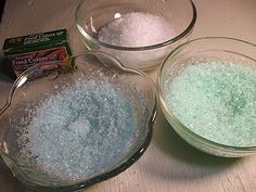 three bowls filled with different colored powdered items on top of a wooden table next to a packet of salt