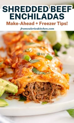 a white plate topped with meat and cheese covered enchilada next to sliced avocado