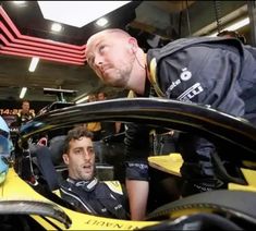 two men sitting in a race car talking to each other