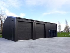 two black garages sitting next to each other on top of a cement floor covered field