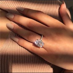 a woman's hand with a ring on her finger and an oval shaped diamond in the middle