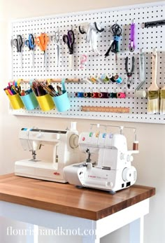 a sewing machine sitting on top of a wooden table next to a wall mounted pegboard