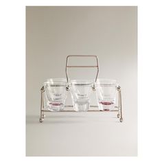 three glasses are sitting on a metal rack with handles and two empty ones in front