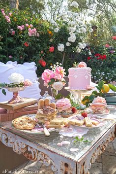 a table topped with cakes and pastries on top of a wooden table covered in flowers