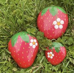 three painted strawberries sitting in the grass