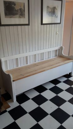 a white bench sitting on top of a black and white checkered floor next to two framed pictures