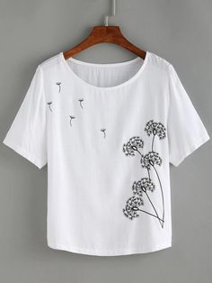 a white t - shirt with dandelions embroidered on the front and back, hanging from a wooden hanger