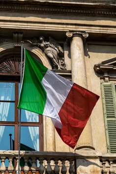 the italian flag is flying in front of an old building