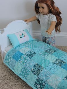 a doll standing next to a bed with a blue quilt on it's cover