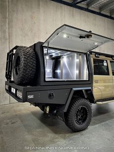 an off - road vehicle parked in a garage with its doors open and lights on