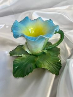 a blue and yellow flower sitting on top of a white cloth covered tablecloth,