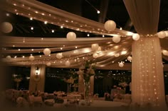 a banquet hall decorated with white lights and paper lanterns