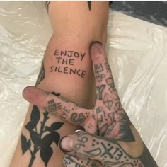 two people with tattoos on their arms and feet, one holding the other's hand