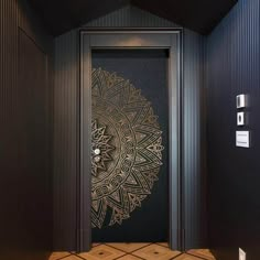 an ornate door is in the middle of a room with black walls and wooden flooring