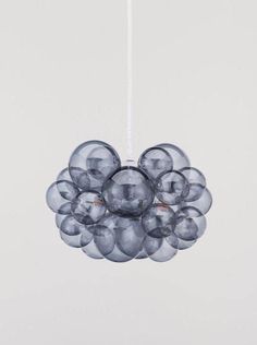 a bunch of clear balls hanging from a white cord in front of a gray wall