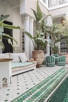 an indoor pool surrounded by potted plants and greenery next to a white couch