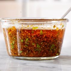 a glass jar filled with red sauce and herbs