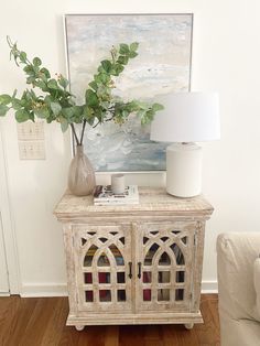 a table with a vase, lamp and painting on the wall