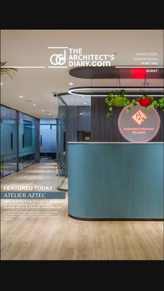 an office with wood flooring and green planters on the front desk, surrounded by glass walls